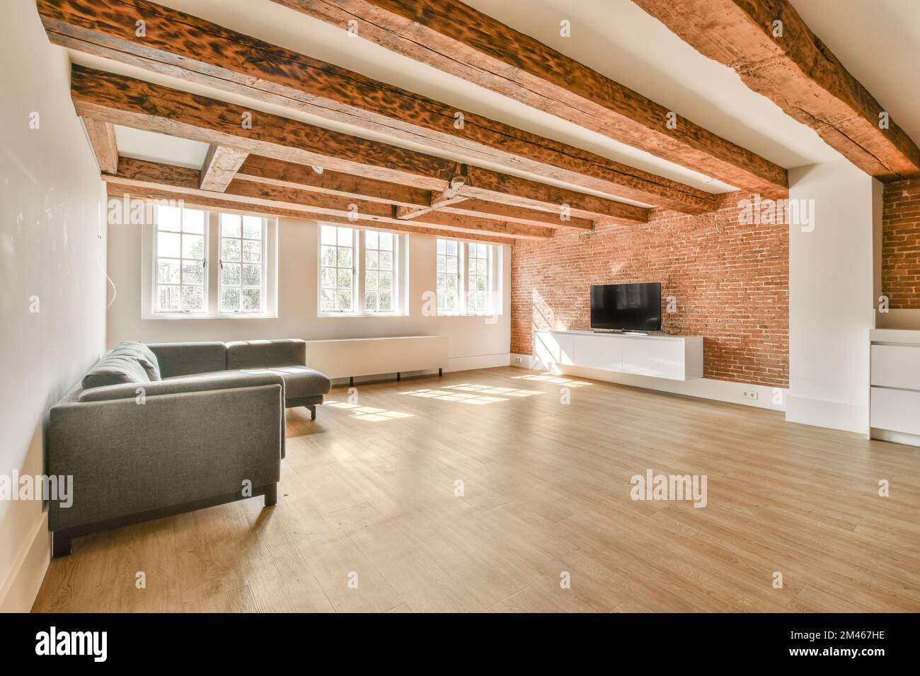 Sofa located near lounge area and kitchen under white ceiling with