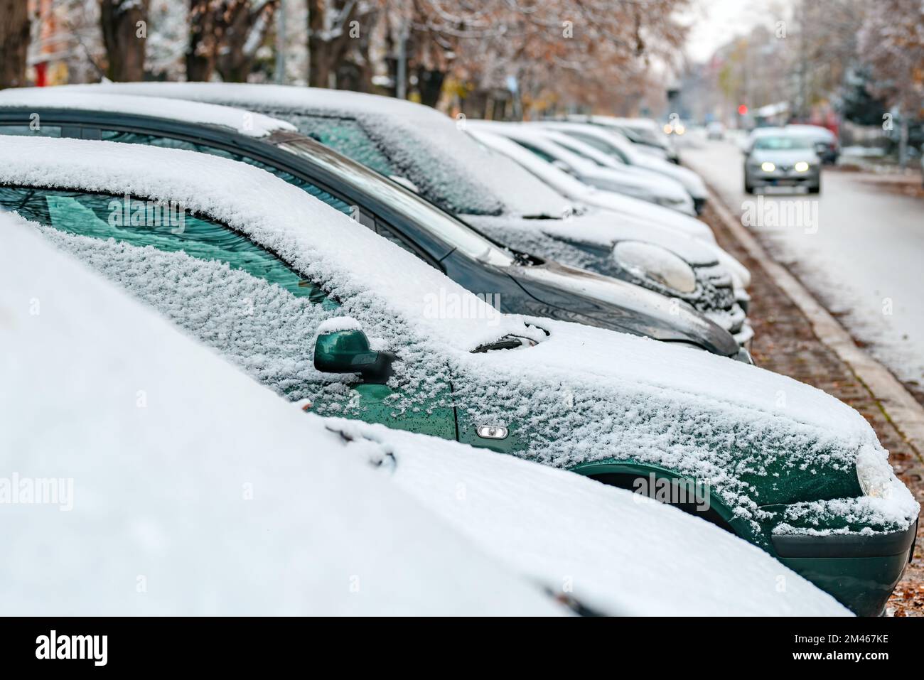 Cars under first snow of the winter on parking lot in residential ...