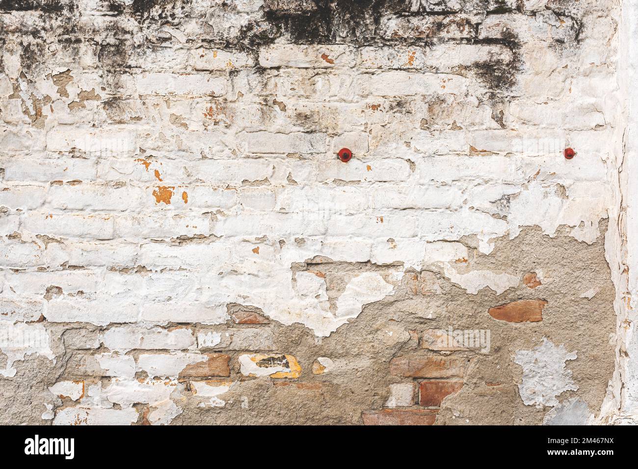 Old brick wall facade texture with white paint peeling off the surface as background Stock Photo