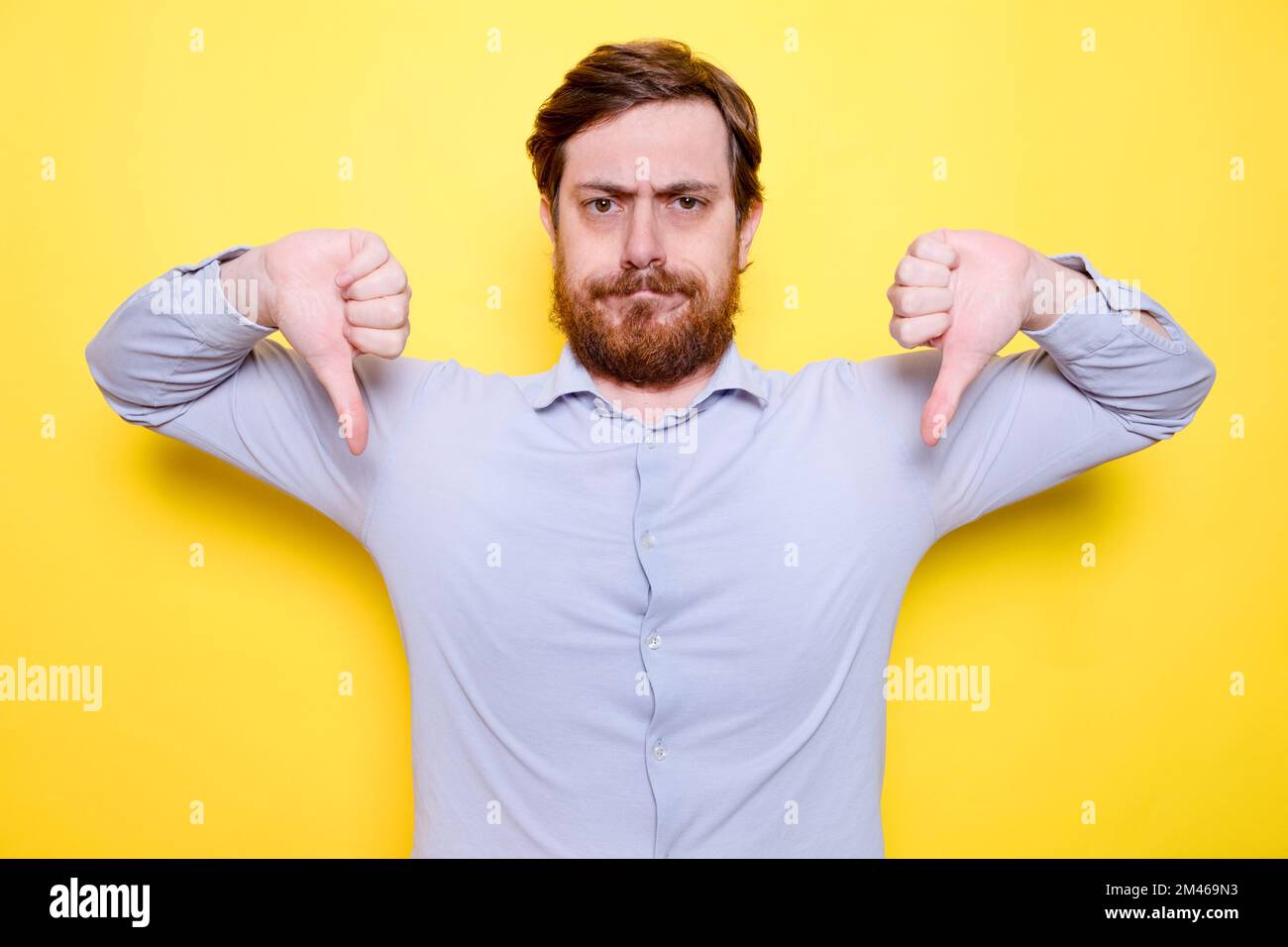 Man isolated on yellow background showing thumb down, disappointment concept Stock Photo