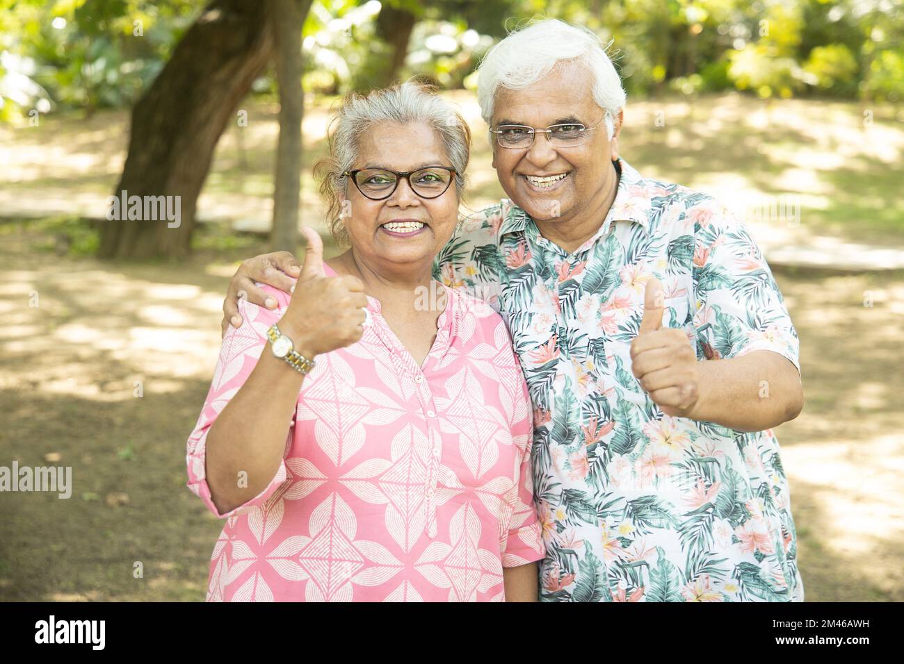 Happy indian senior couple give thumbs up pose at summer park. Old people enjoying life. Stock Photo