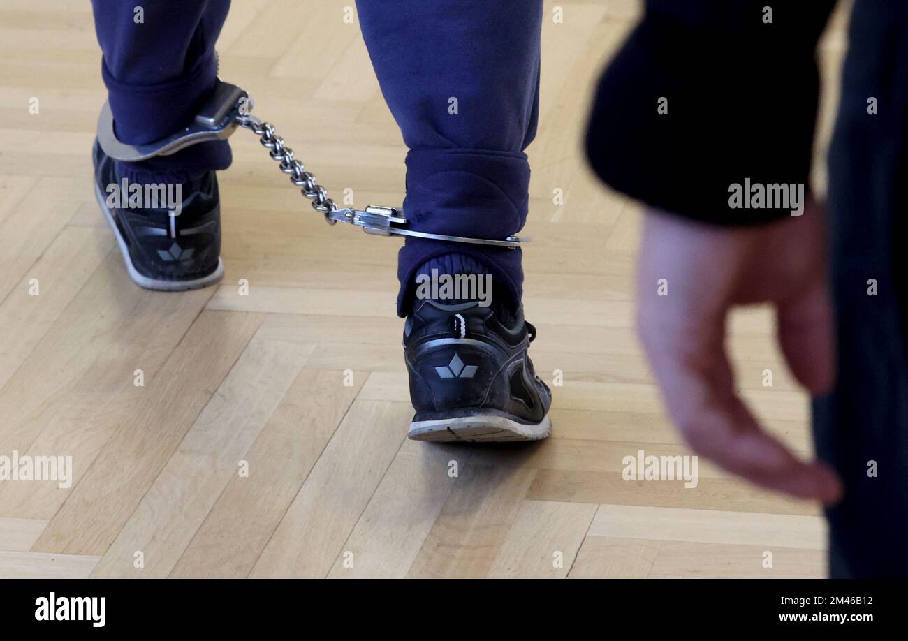 Rostock, Germany. 19th Dec, 2022. The defendant in the triple murder trial is led into the courtroom wearing an ankle bracelet. The 27-year-old man allegedly murdered his parents and sister. Credit: Bernd Wüstneck/dpa/Alamy Live News Stock Photo