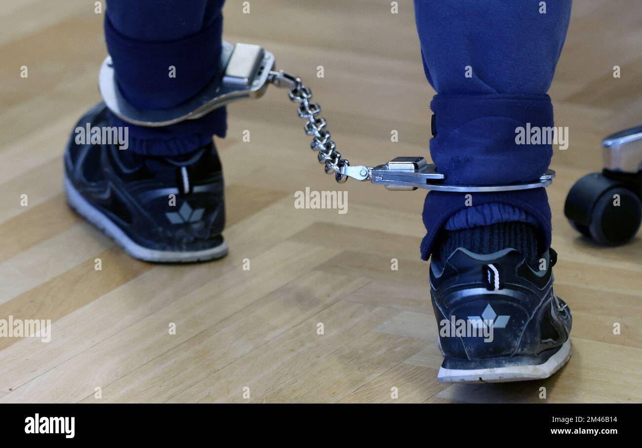 Rostock, Germany. 19th Dec, 2022. The defendant in the triple murder trial is led into the courtroom wearing an ankle bracelet. The 27-year-old man allegedly murdered his parents and sister. Credit: Bernd Wüstneck/dpa/Alamy Live News Stock Photo