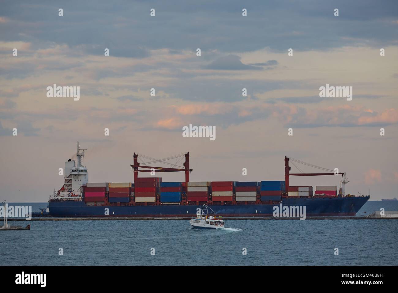 A large merchant ship container vessel in coastal waters of ocean. A merchant ship is moving around sea in daytime Stock Photo