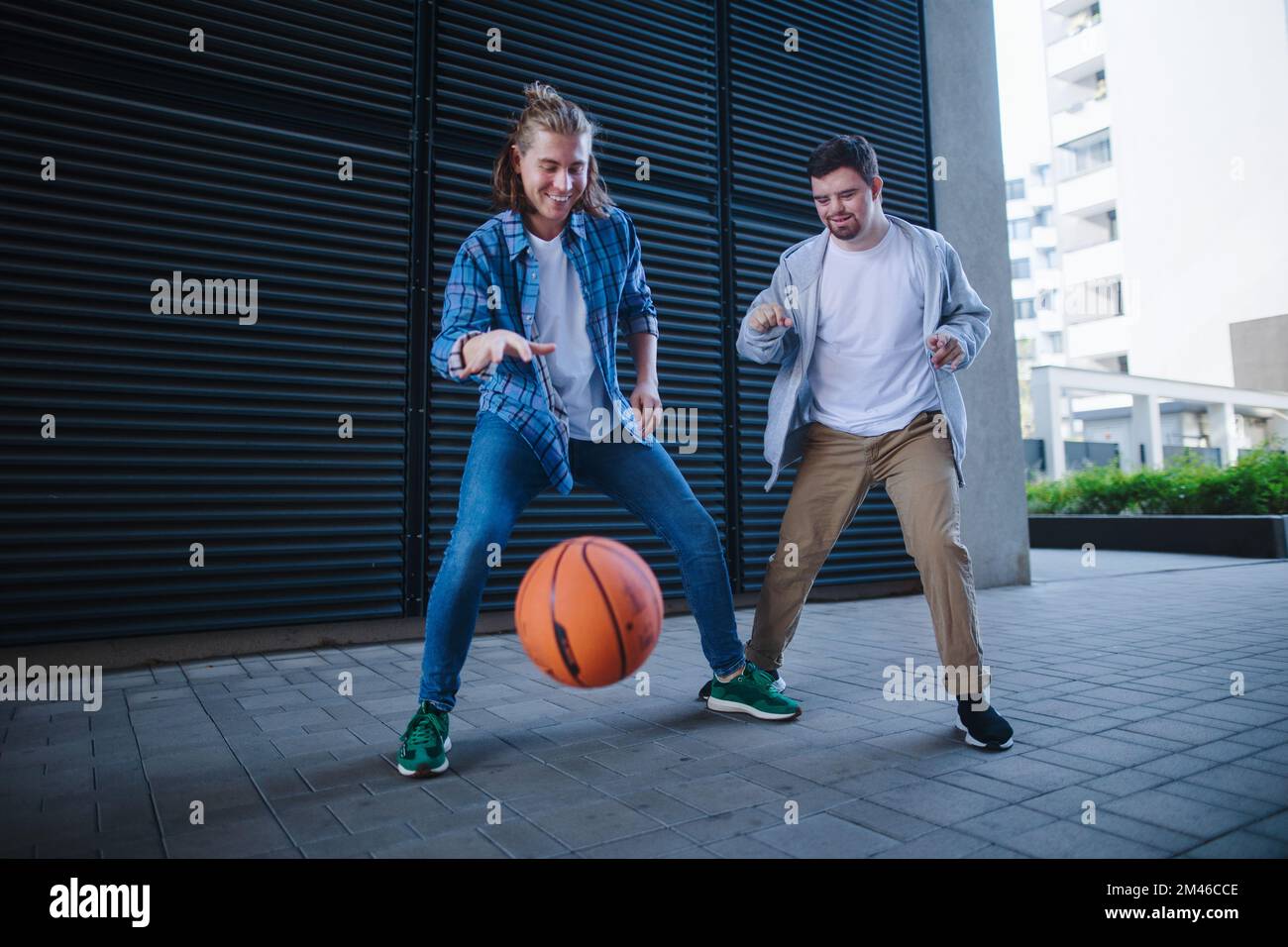 Man with down syndrome playing basketball outdoor with his friend