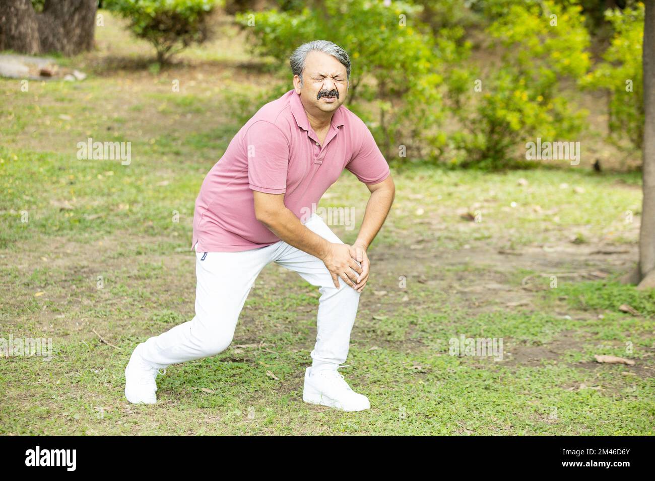 Indian senior man suffering from knee pain.Asian Old male injured his leg while running outdoor at park. Stock Photo
