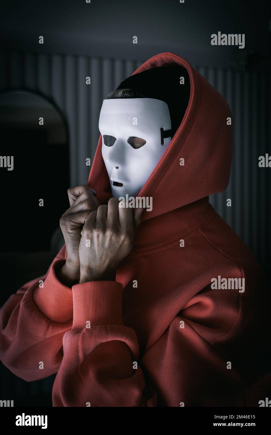 Portrait of woman in white theater mask and hood on black background. Concept of mental disorders, hypocrisy. High quality photo Stock Photo