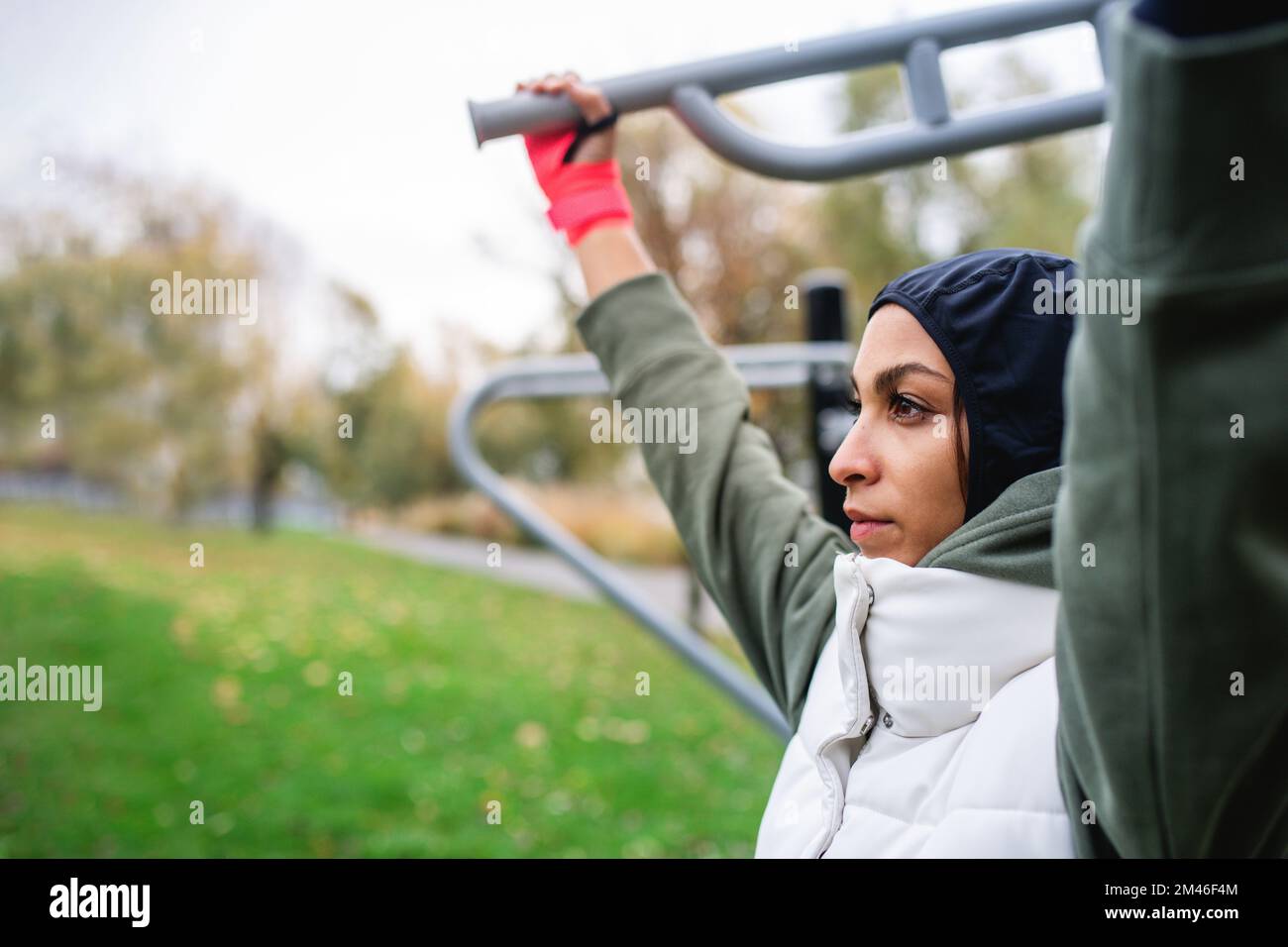 Young muslim woman in sports hijab doing work out in outdoor training ground. Stock Photo