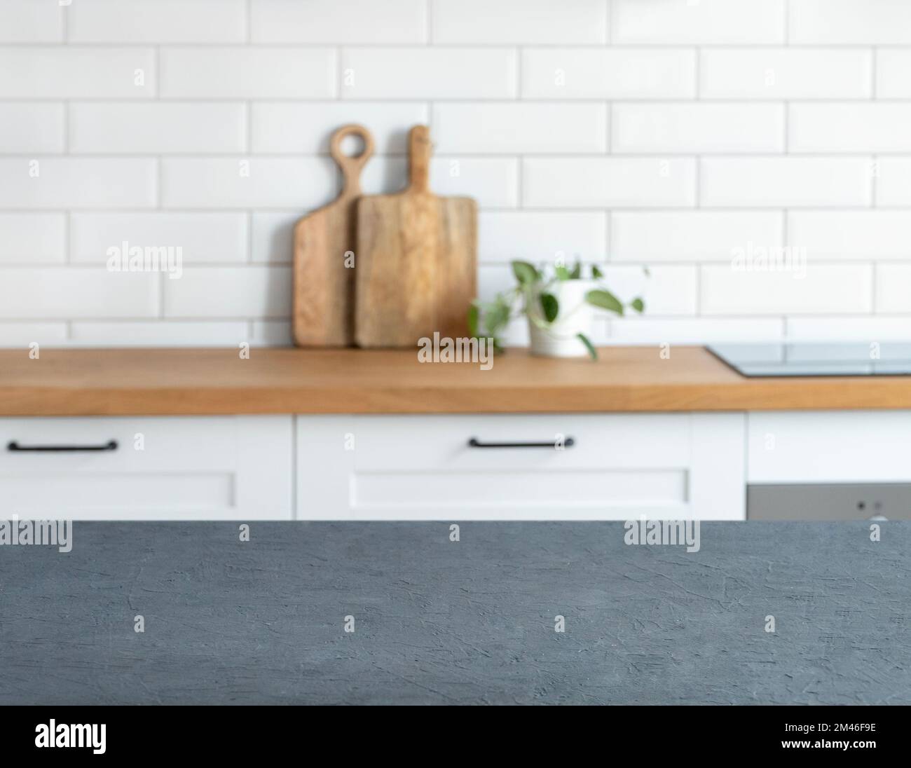 Wooden blue countertop with free space for mounting a product or layout against the background of a blurred white kitchen with cutting board and plant Stock Photo