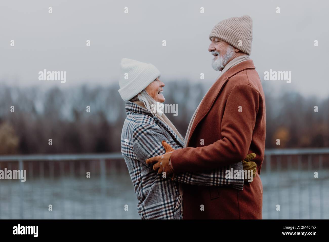 Elegant senior couple walking near the river, during cold winter day. Stock Photo