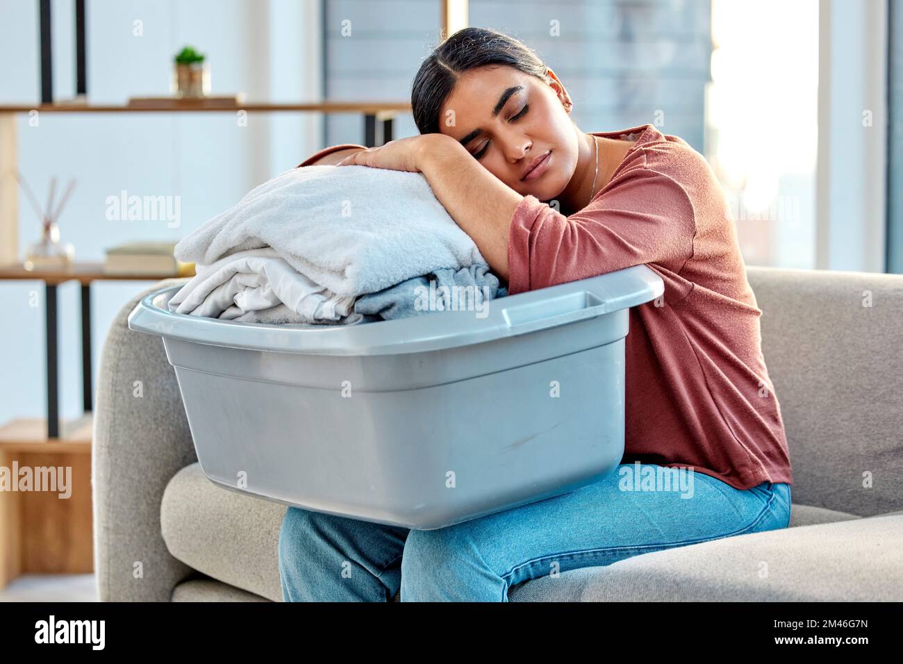Woman, sleeping and laundry basket on sofa from cleaning, folded