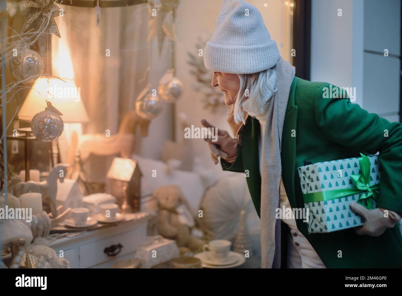 Senior woman looking in window display with Christmas decorations. Stock Photo