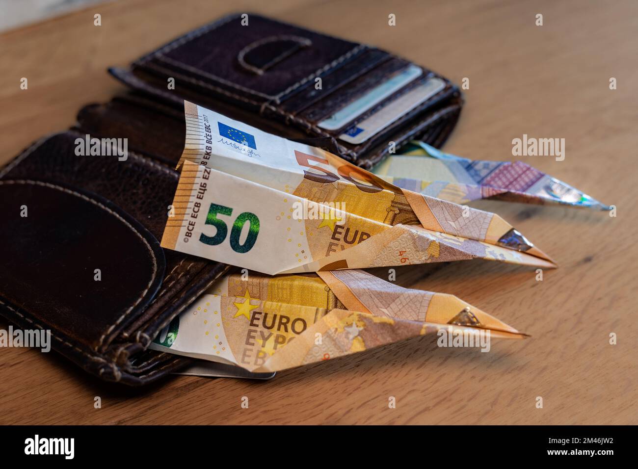 Banknotes looking out of a wallet. Are folded into a paper airplane Stock Photo