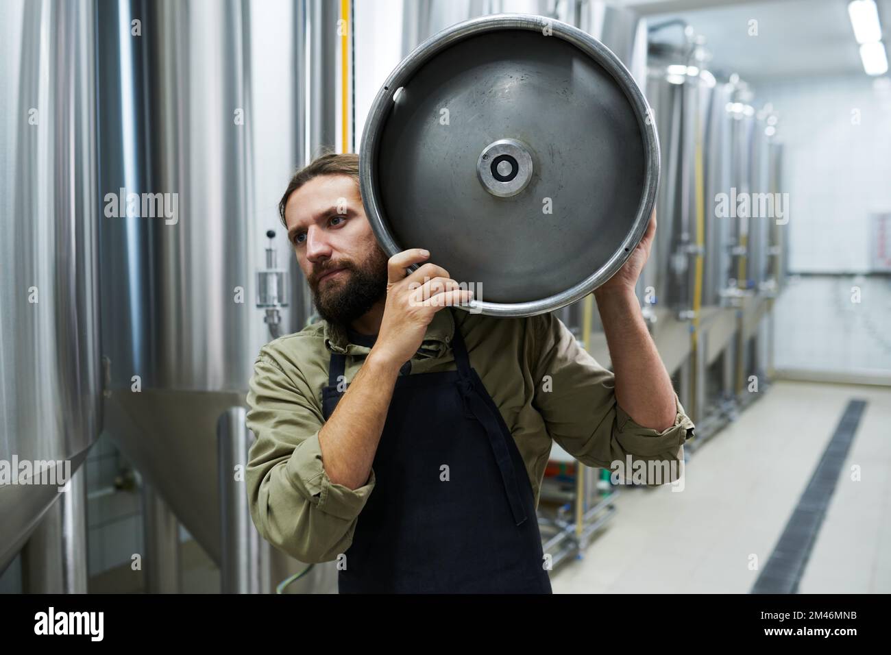 Microbrewery owner carrying keg with drink to warehouse Stock Photo