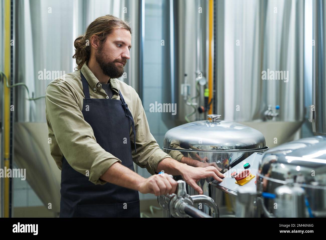 Brewery worker looking at small screen when setting proper pressure for fermenting process Stock Photo