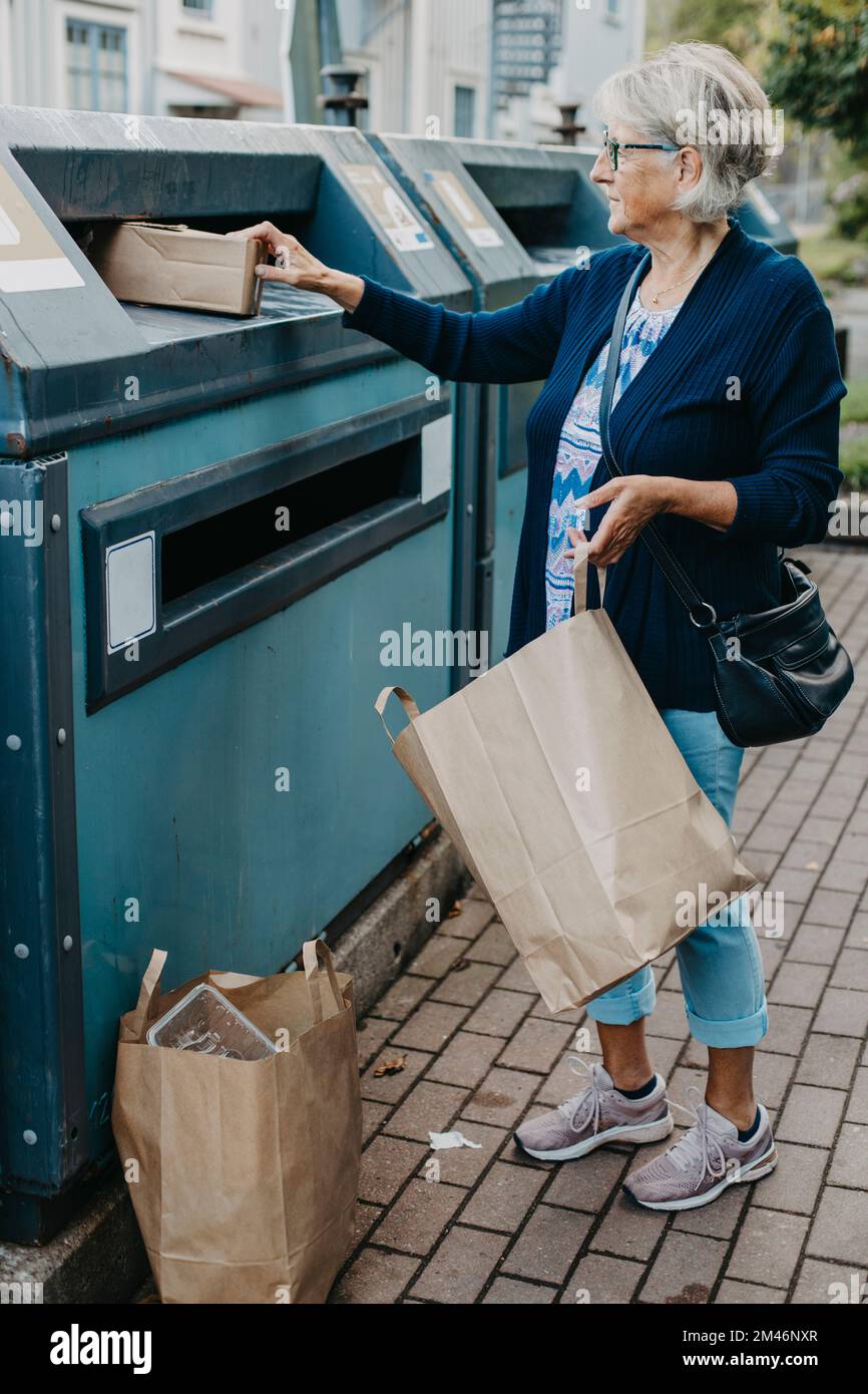 Woman putting cardboard in recycling bin Stock Photo Alamy