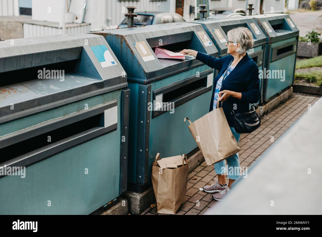 Woman putting paper in recycling bin Stock Photo Alamy