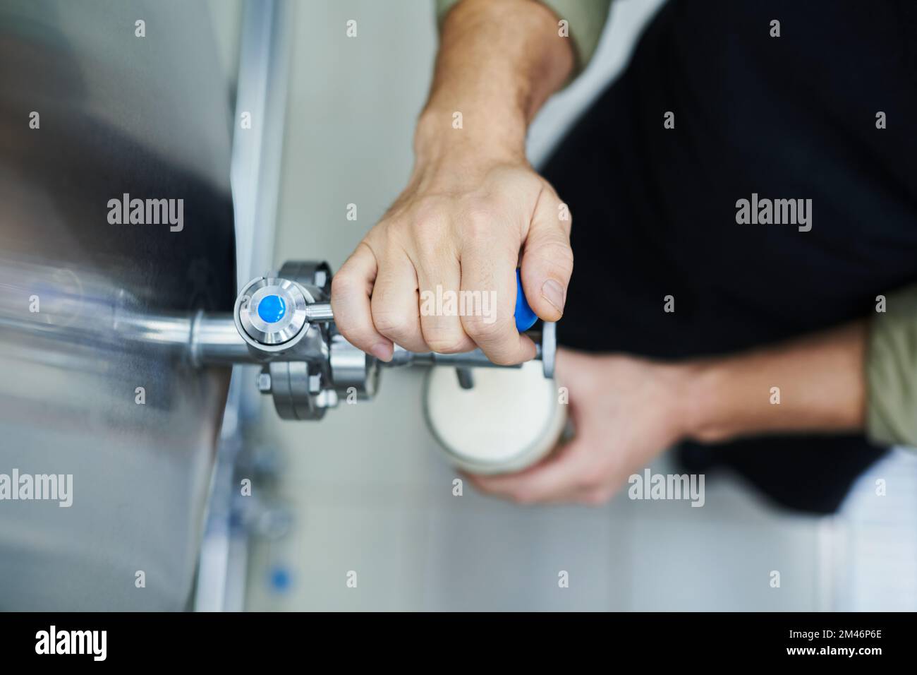 Close-up image of brewery worker pouring beer from tank in big glass Stock Photo