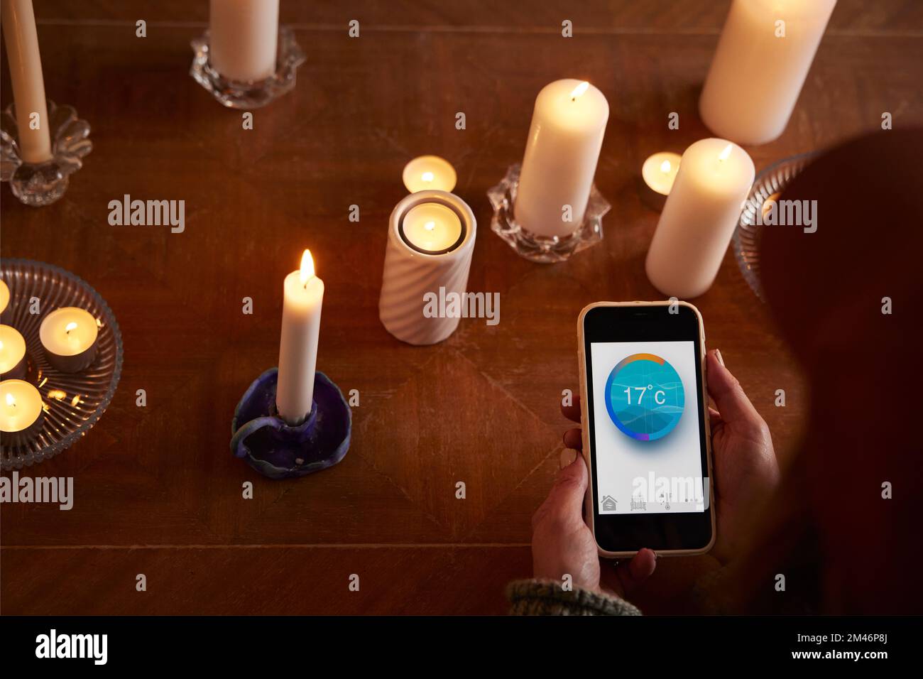 Woman lighting candles and using temperature app Stock Photo Alamy