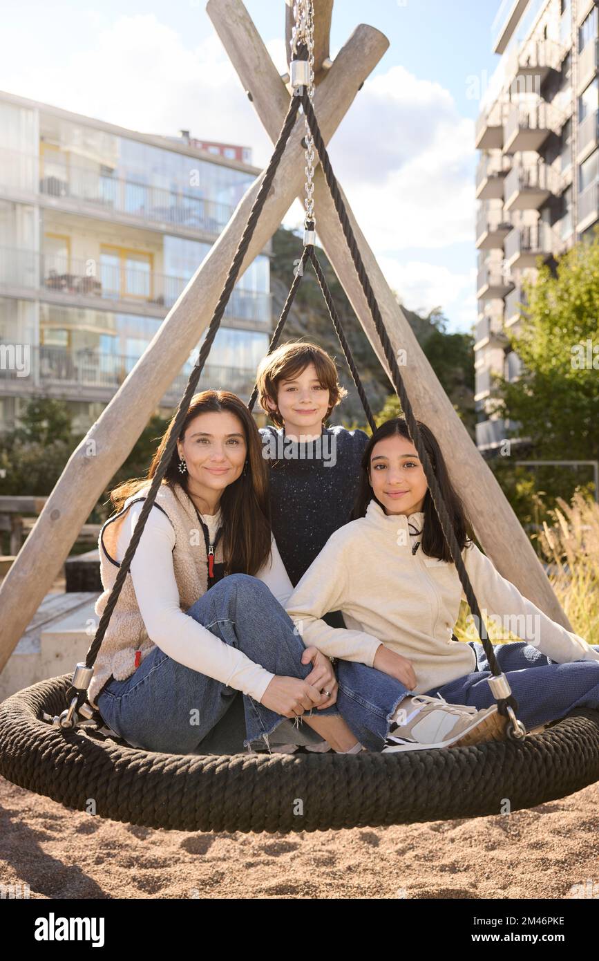 Mother with children on swing Stock Photo