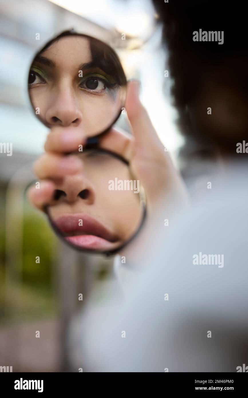 Young woman reflecting in hand mirror Stock Photo