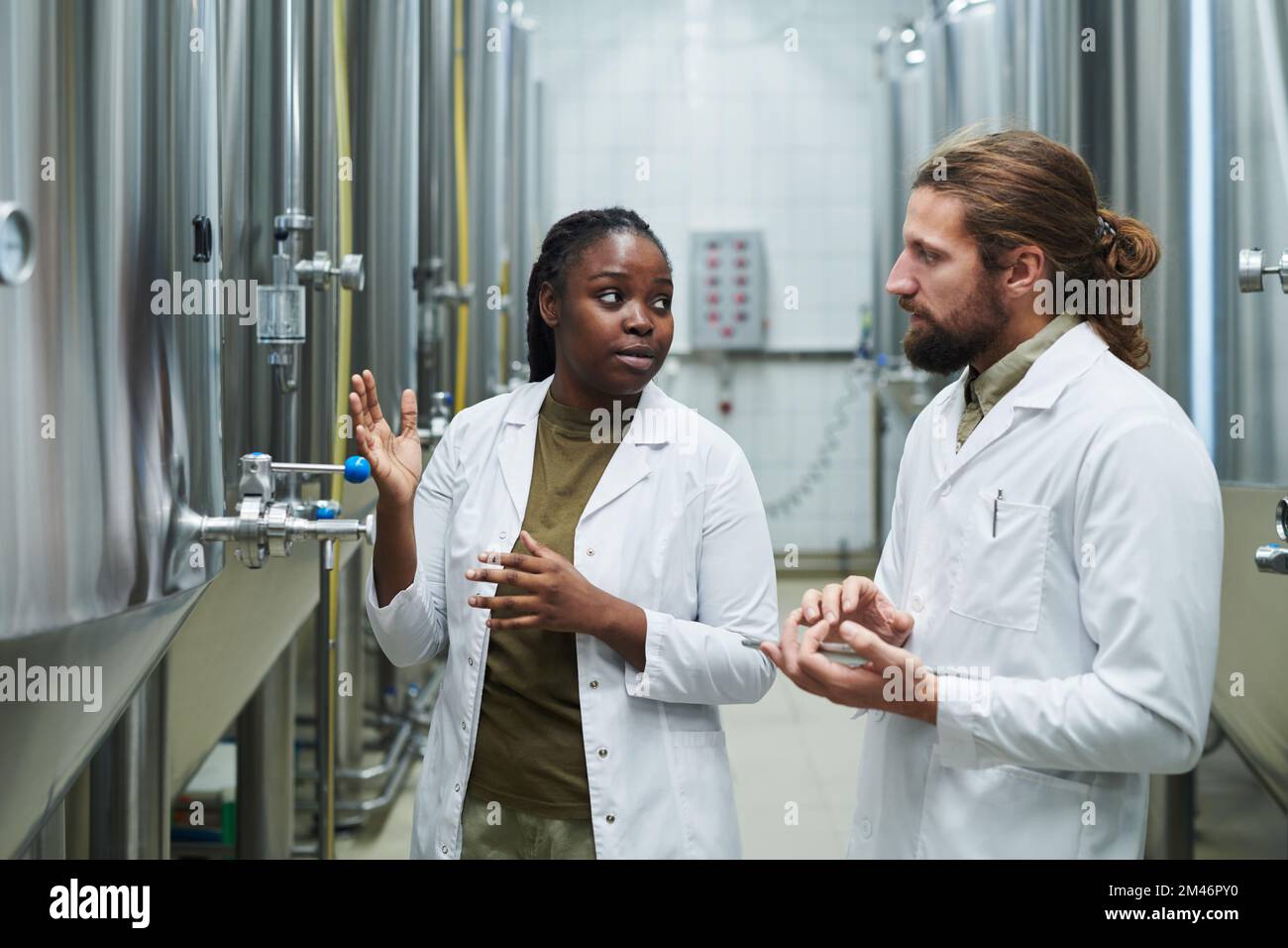 Brewing factory worker in white labcoat showing equipment to inspector Stock Photo