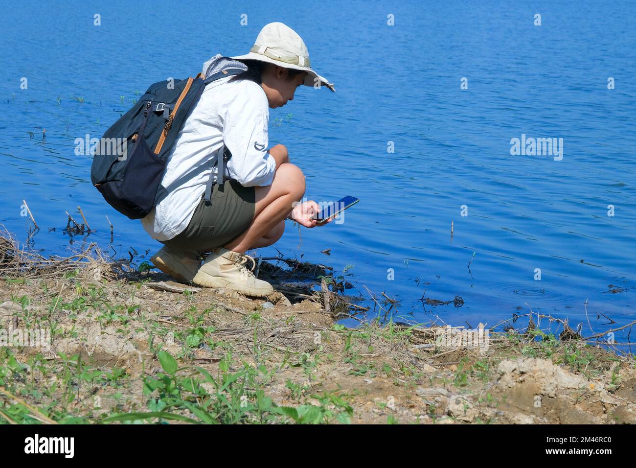 Female environmentalist using mobile phone to record analysis of pathogens in natural waters. Water and ecology concept Stock Photo