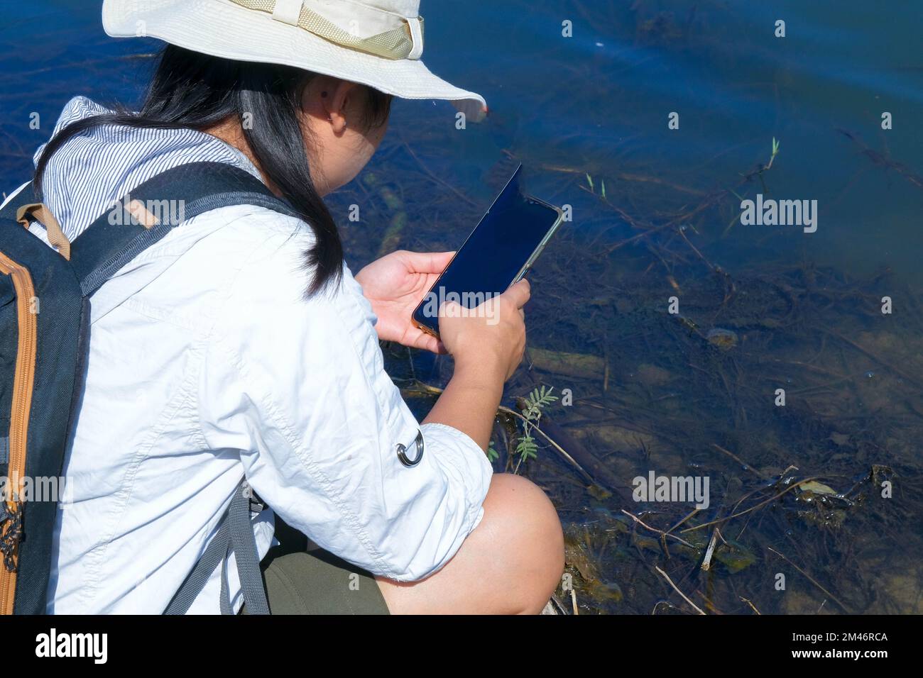 Female environmentalist using mobile phone to record analysis of pathogens in natural waters. Water and ecology concept Stock Photo