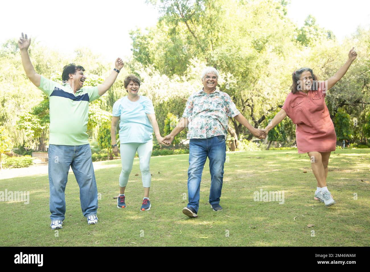 Group of happy indian senior men and women laughing and walking together in summer park. Retirement life, retired people enjoying in garden. having fu Stock Photo