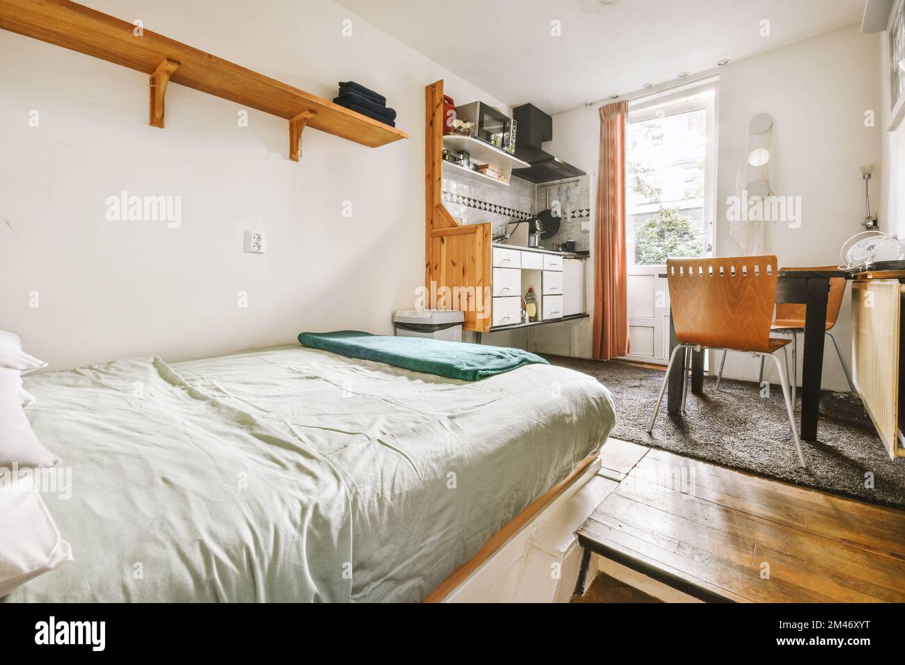 a bedroom with a bed, desk and shelves on the wall next to an open door ...