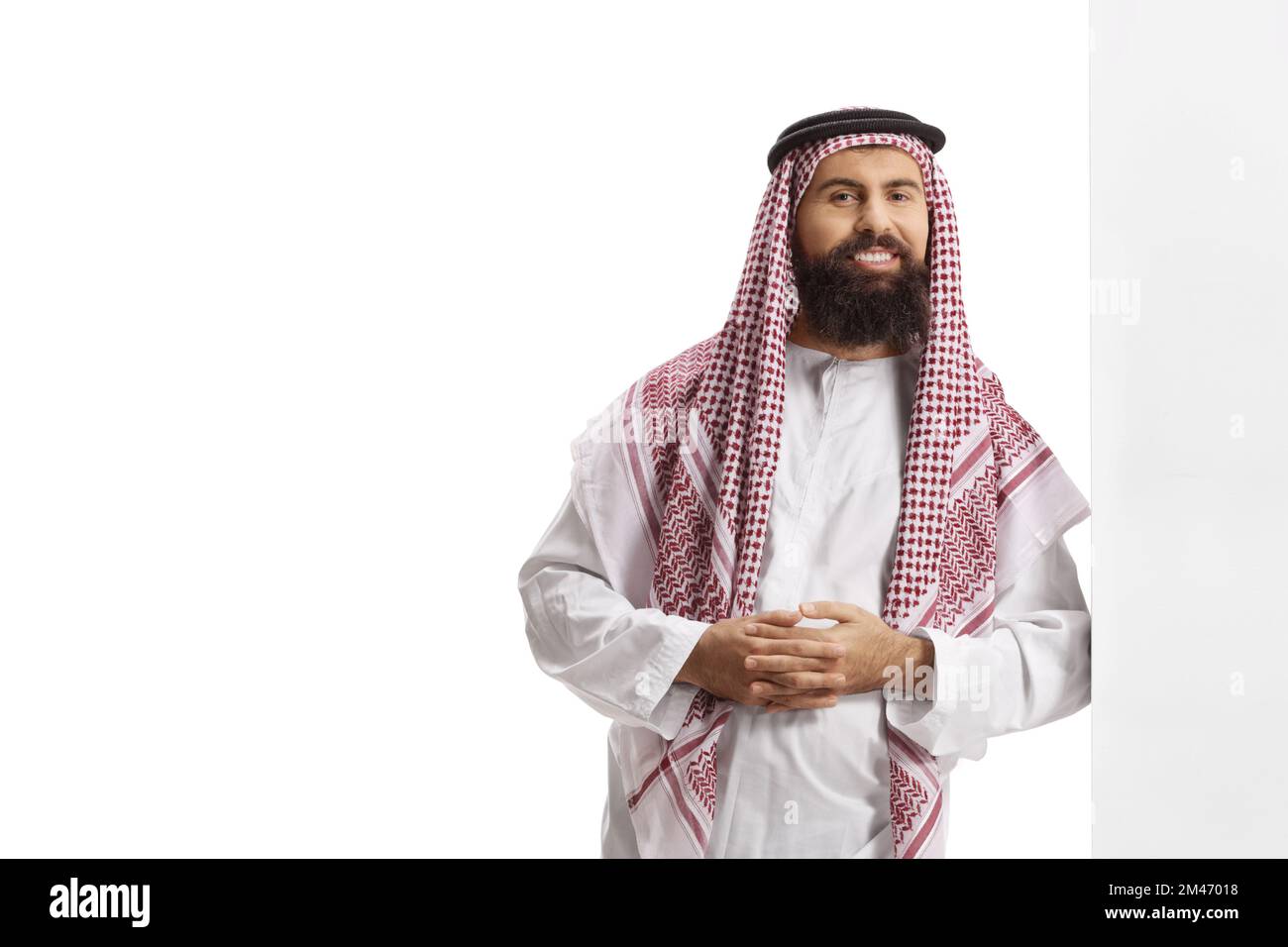 Saudi arab man wearing a traditional thobe and leaning on a wall isolated on white background Stock Photo