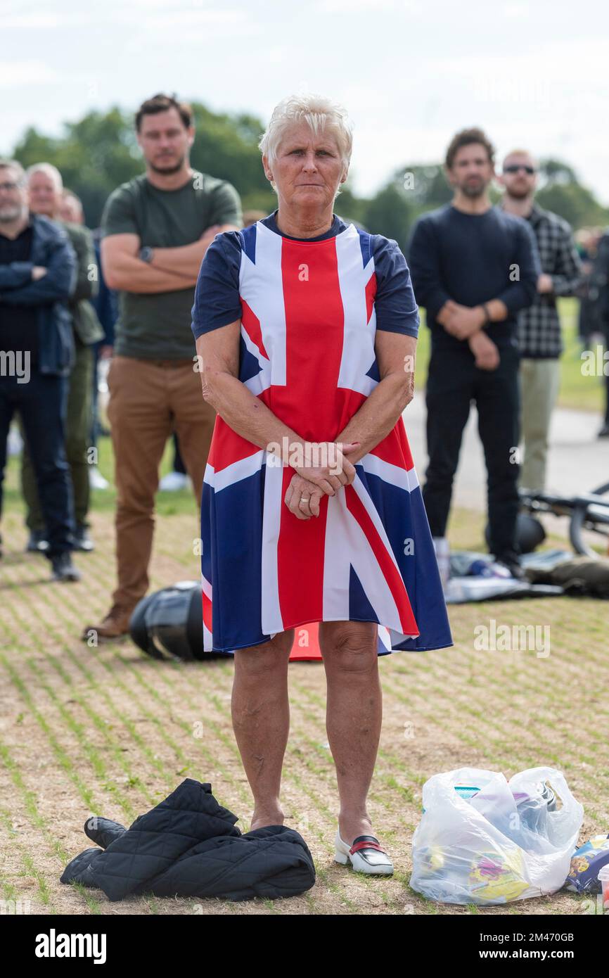 A woman mourner wearing a Union Jack dress, in Hyde park watching the live broadcast of the funeral Her Majesty Queen Elizabeth II taking place in Wes Stock Photo