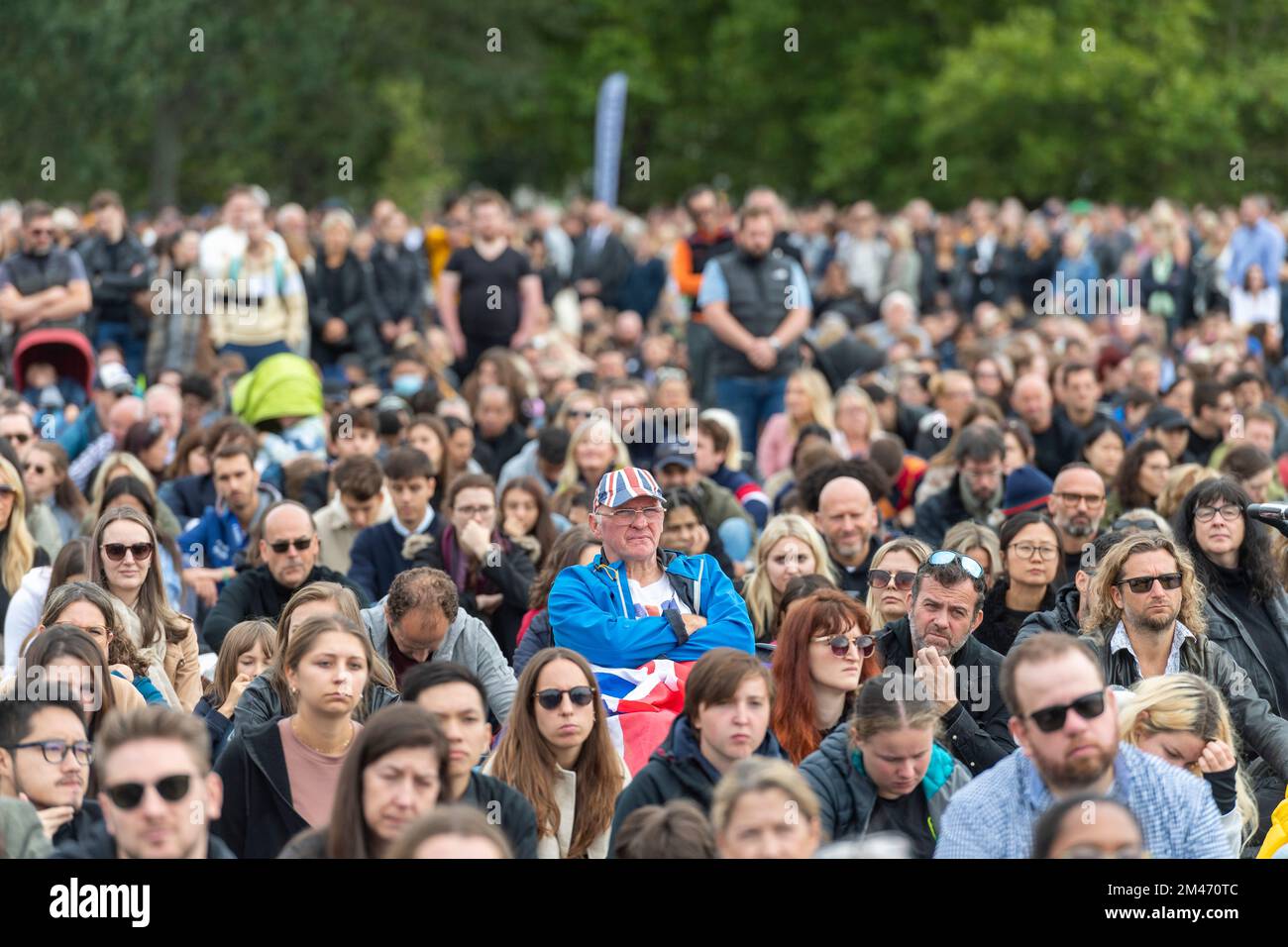 A male mourner wearing a Union Jack hat, in Hyde park watching the live broadcast of the funeral Her Majesty Queen Elizabeth II taking place in Westmi Stock Photo