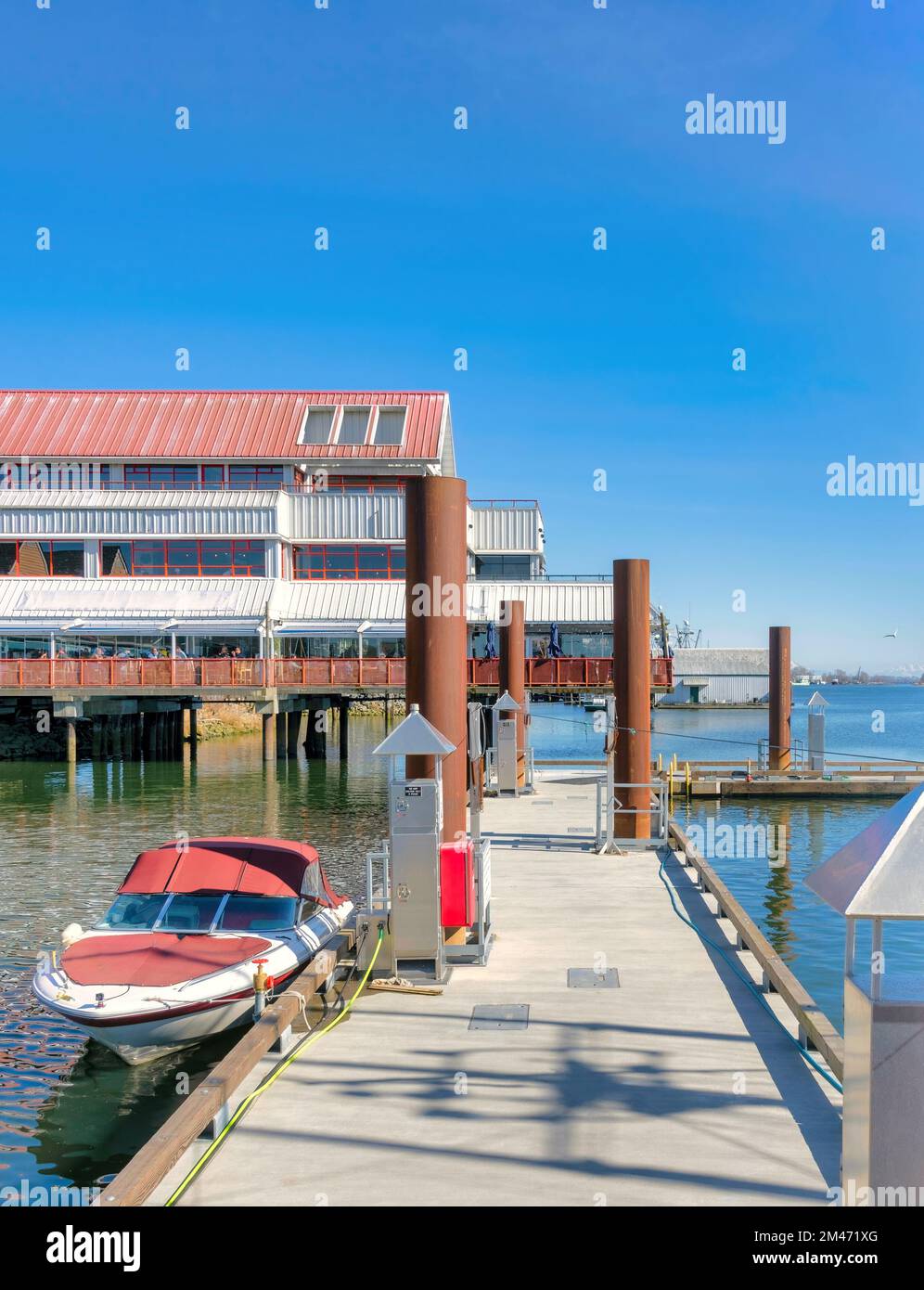 Motorized boat moored at the pier with seafood restaurant on the background Stock Photo