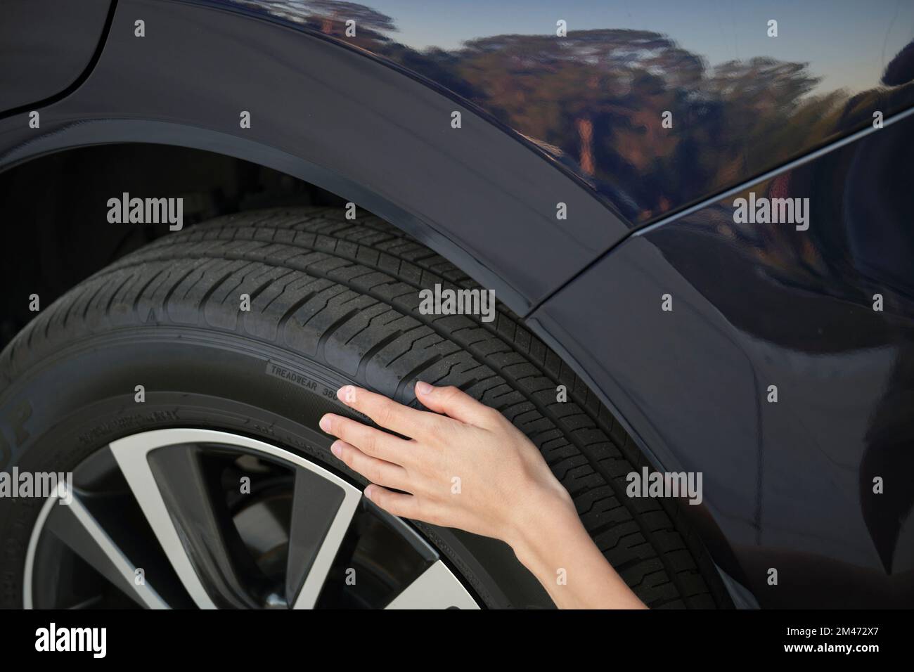 Female driver hands inspecting wheel tire of her new car. Vehicle safety concept Stock Photo