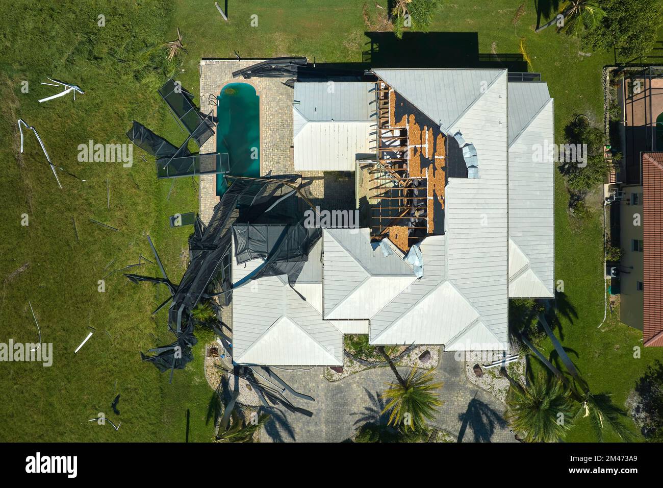 Hurricane Ian destroyed swimming pool lanai enclosure on house yard in Florida residential area. Natural disaster and its consequences Stock Photo
