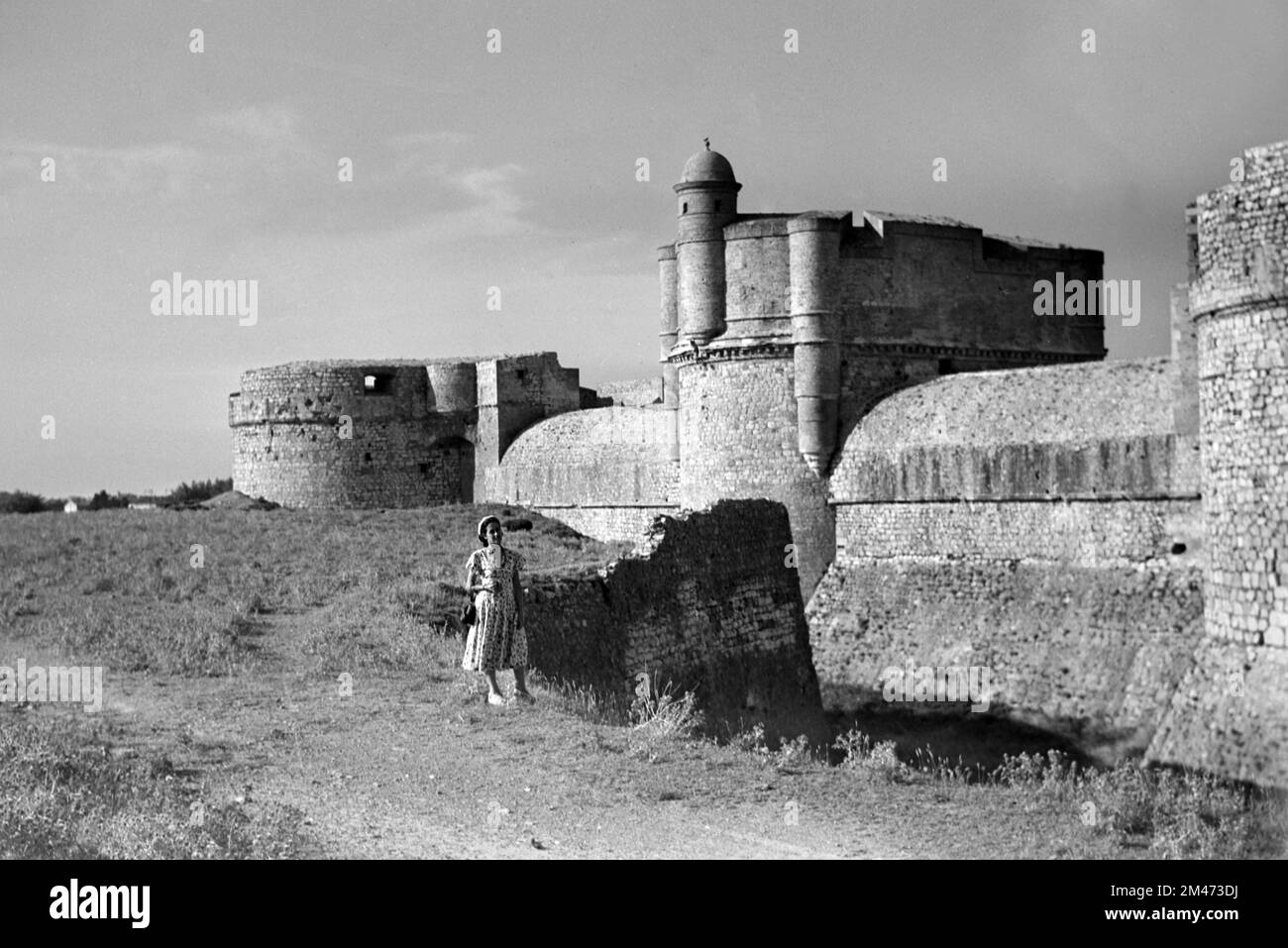 Young 1950s Woman Tourist poses in Front of the Moat and Ramparts of the Salses Fort or Fortress at Salses-le-Château 1951 Stock Photo