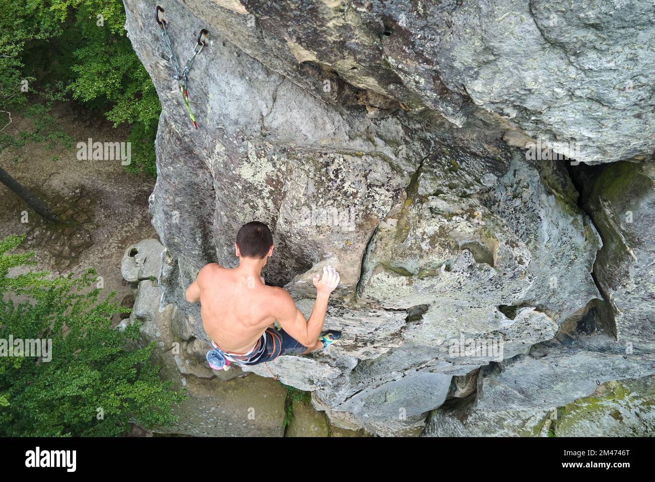 Strong male climber climbing steep wall of rocky mountain. Sportsman