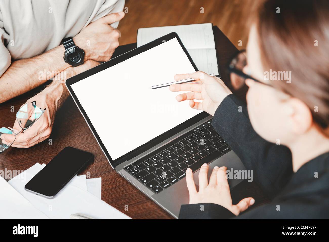 Blank screen of laptop on job desk in office and two business people. Stock Photo