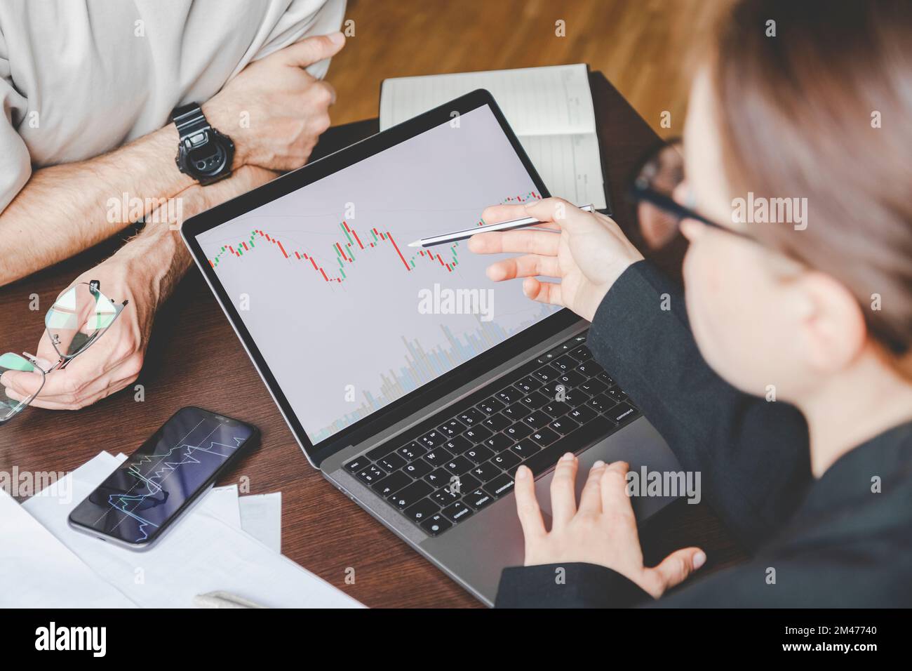 Adult female manager in glasses discusses with male colleague cryptocurrency trends. Stock Photo
