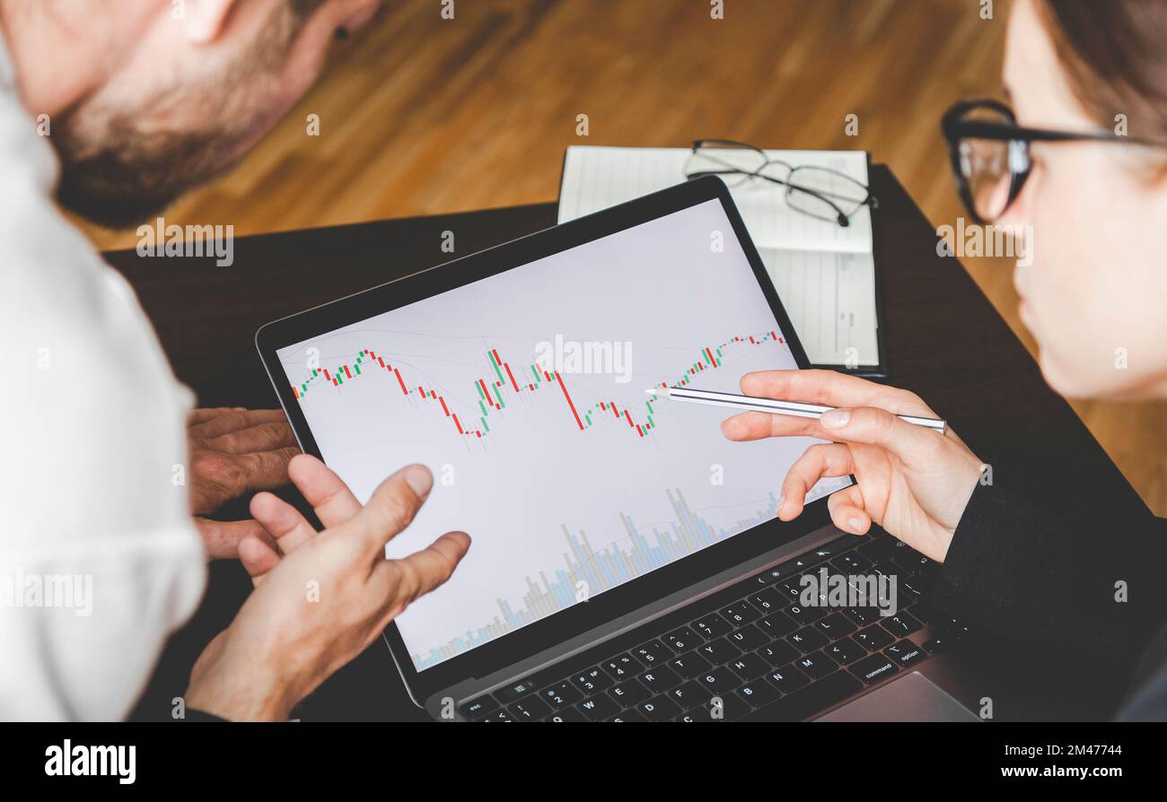 Business people working together analyzing the cryptocurrency chart on the laptop display. Stock Photo