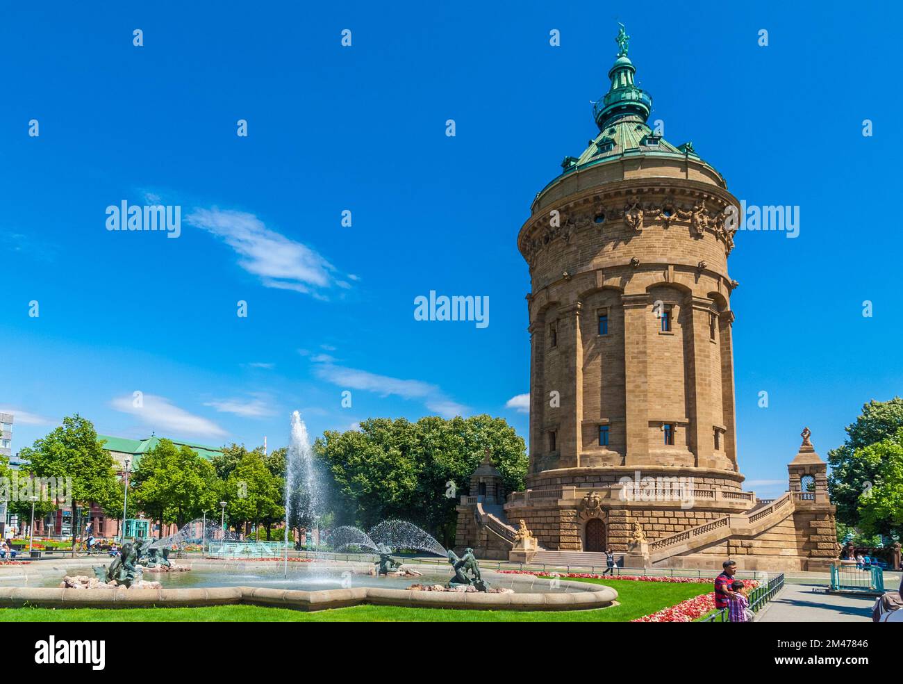 Picturesque view of the famous Water Tower (Wasserturm) and the fountain with water spouts in front on a sunny day with a blue sky in Mannheim,... Stock Photo