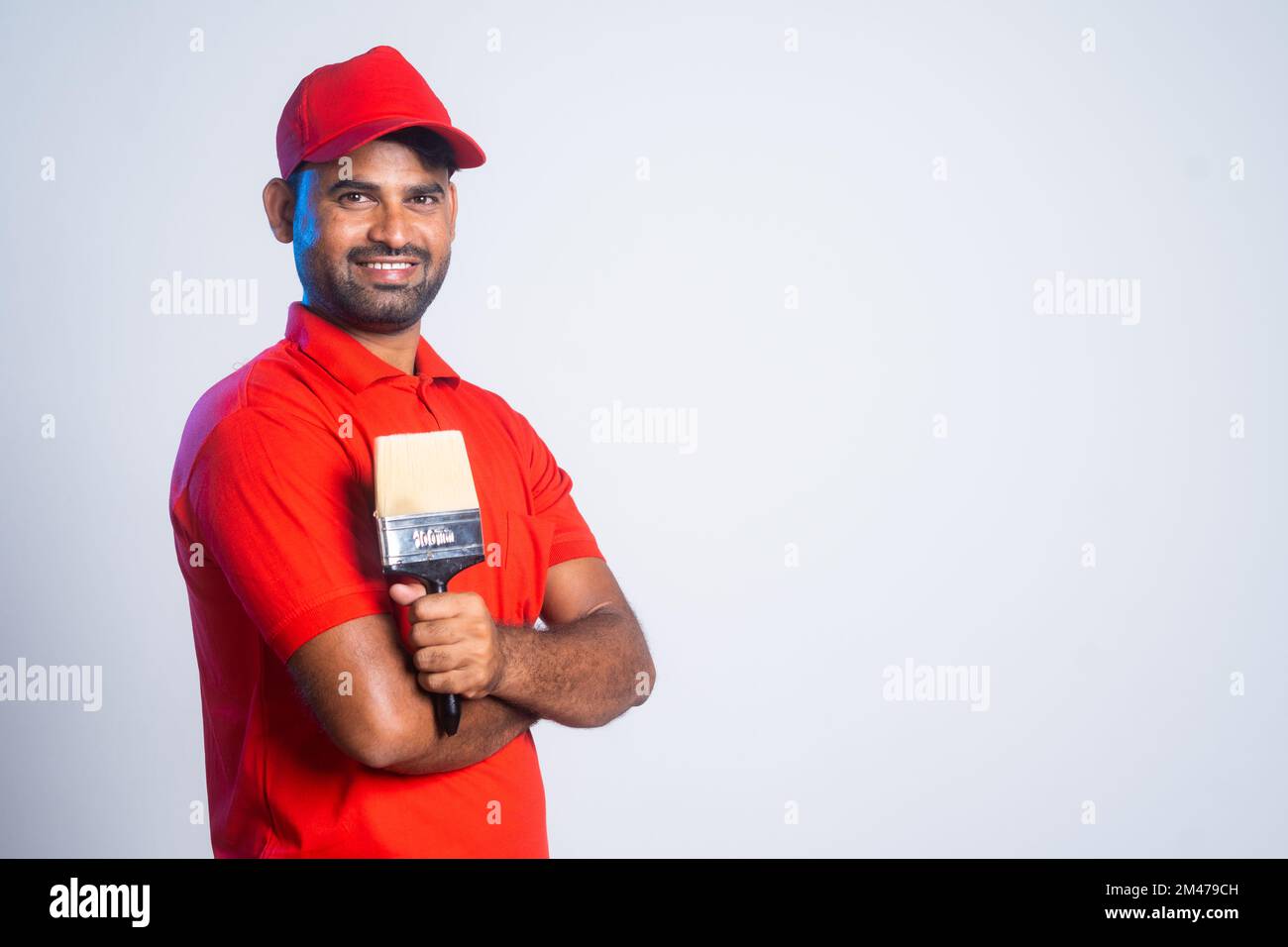 Confident painter standing with crossed arms by holding paint brush by