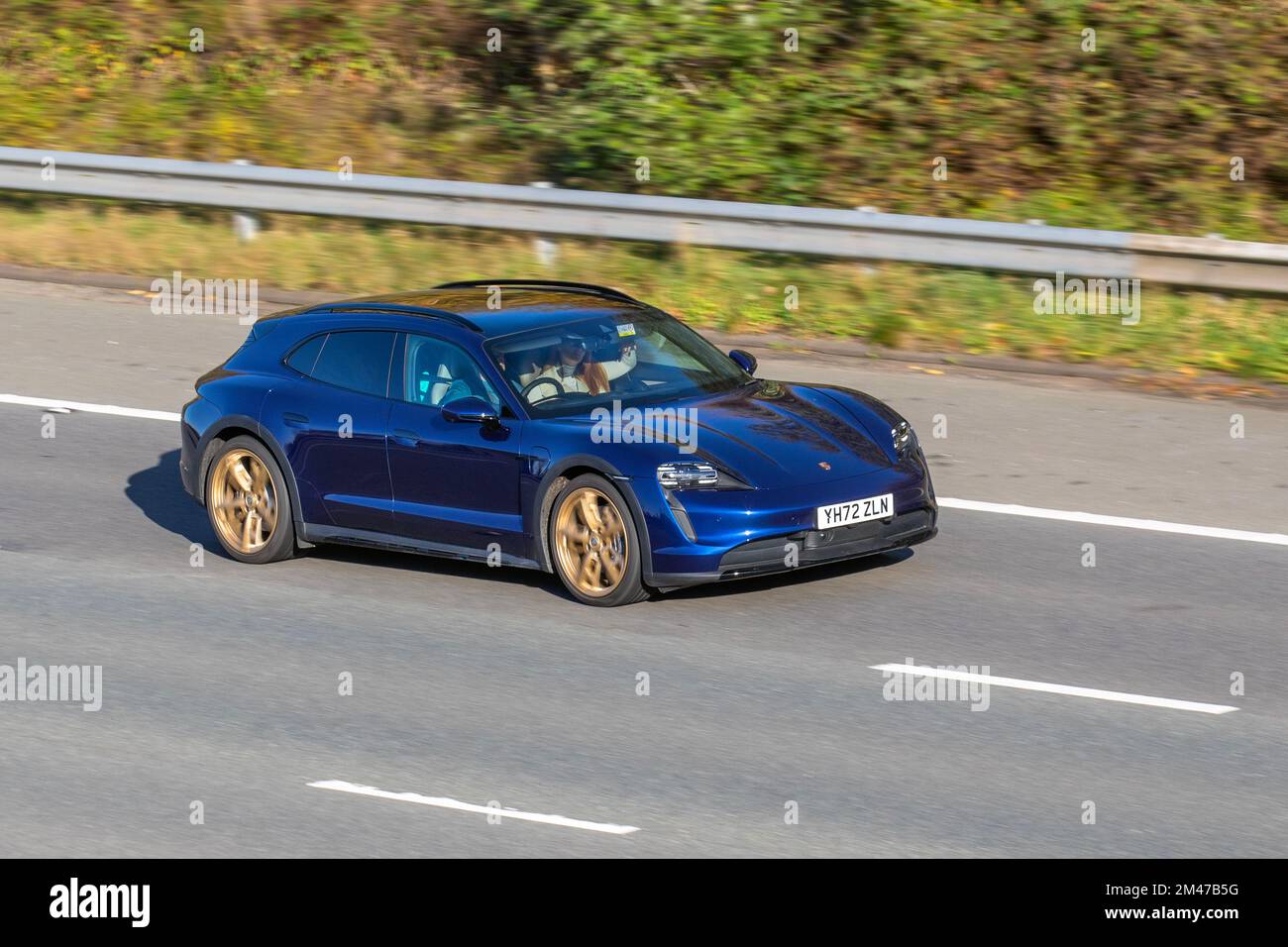 2022 Blue PORSCHE TAYCAN 4 CROSS TURISMO 4S Electricity 1 speed automatic, 93.4kWh Performance Battery Plus with gold alloy wheels; travelling on the M6 motorway UK Stock Photo