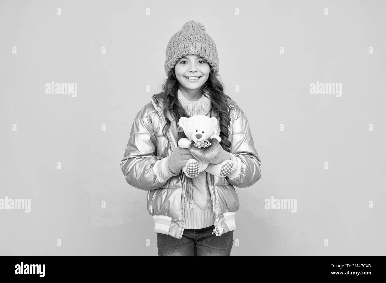 happy kid in puffer jacket and hat. childhood. teen girl hold toy bear. Stock Photo