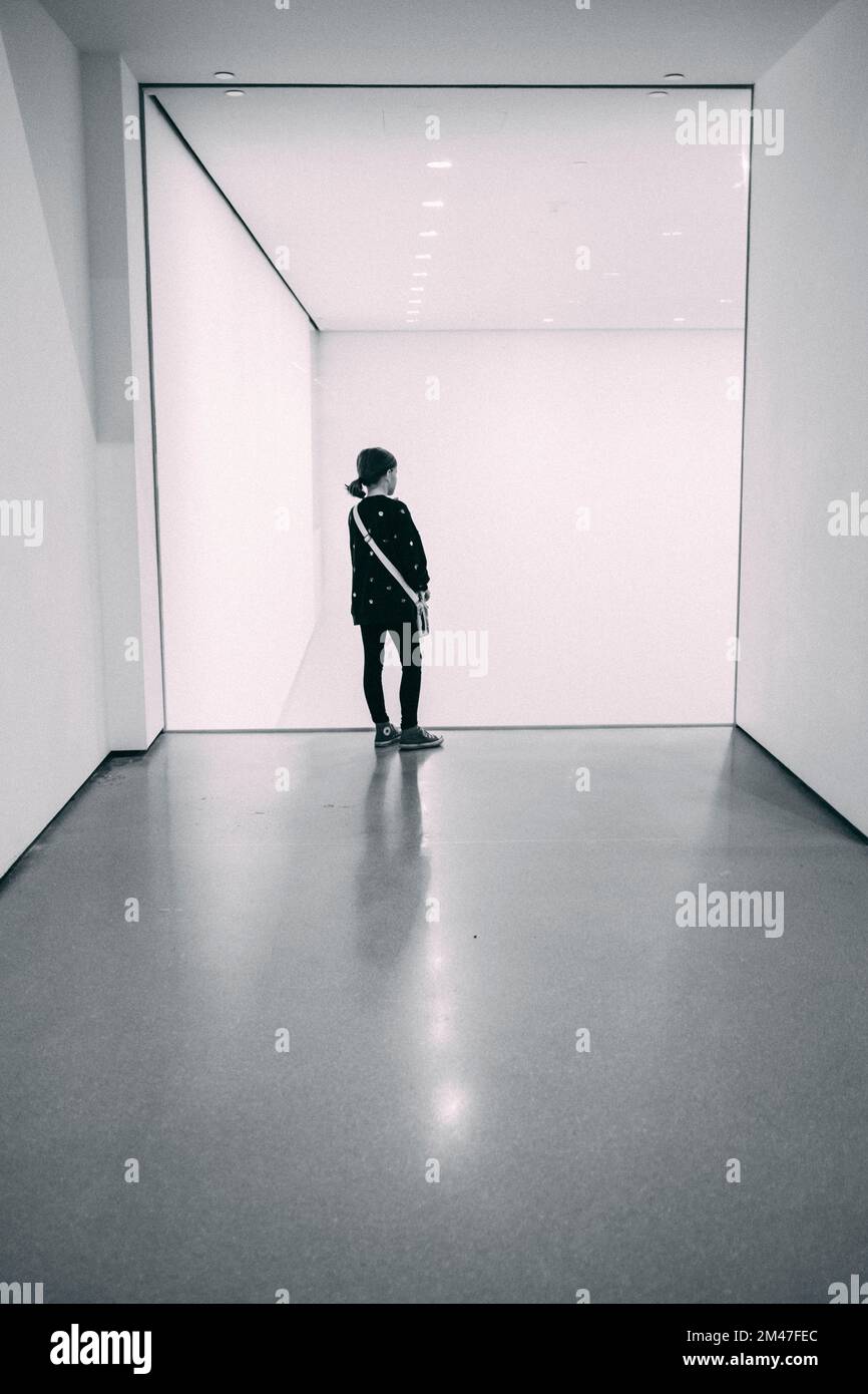 New York Manhattan, 02.10 - 10.10.22: Ein kleines Mädchen schaut allein und verträumt an einer Glasscheibe, im Moma, Museum of modern art.  Foto: pres Stock Photo