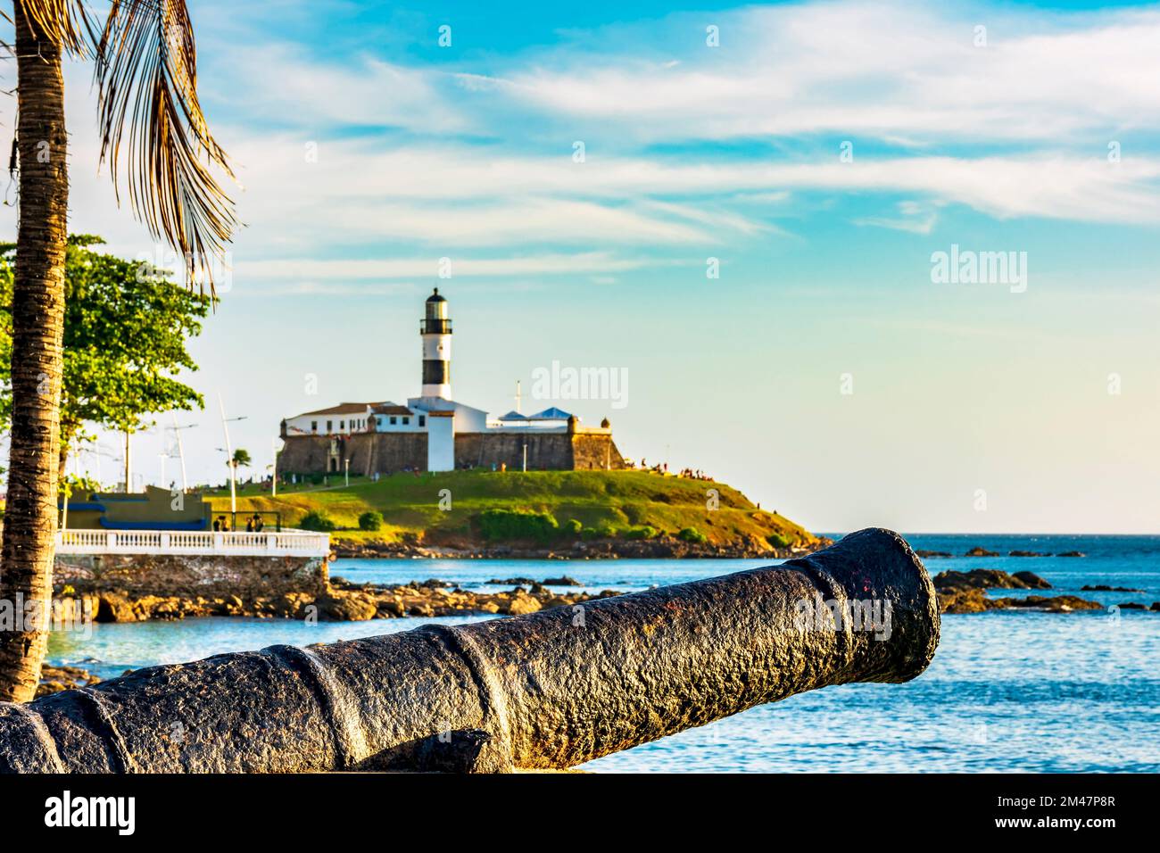 Old cannon and the Barra Lighthouse one of the main historical buildings and tourist spot in the city of Salvador in Bahia surrounded by the sea durin Stock Photo