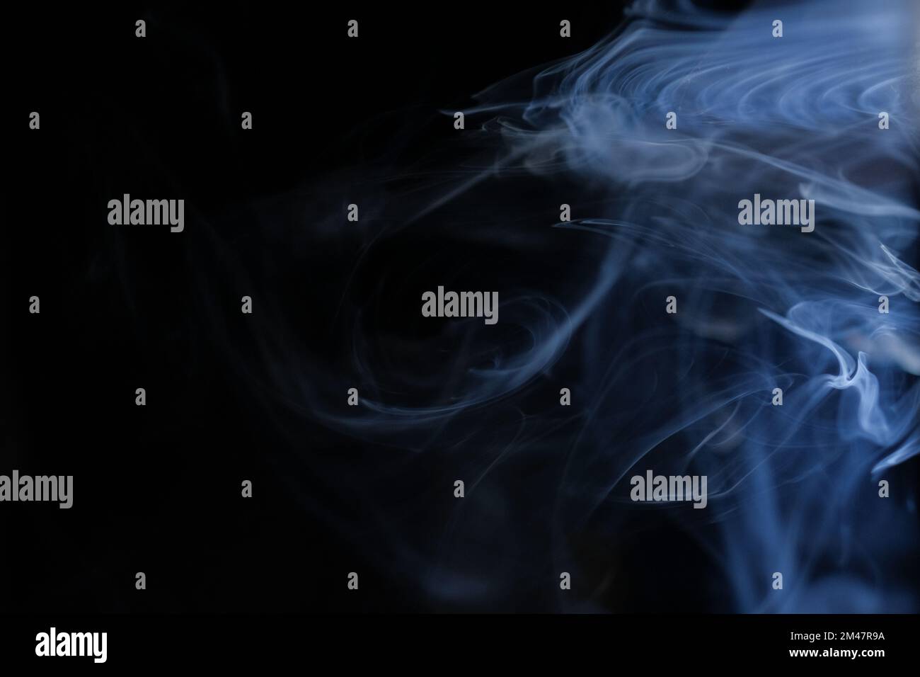 Graceful swirls of blue smoke isolated from black background. Close-up of vapor. Soft focus and texture from vintage Helios 44m-4 lens. Abstract texture. Stock Photo