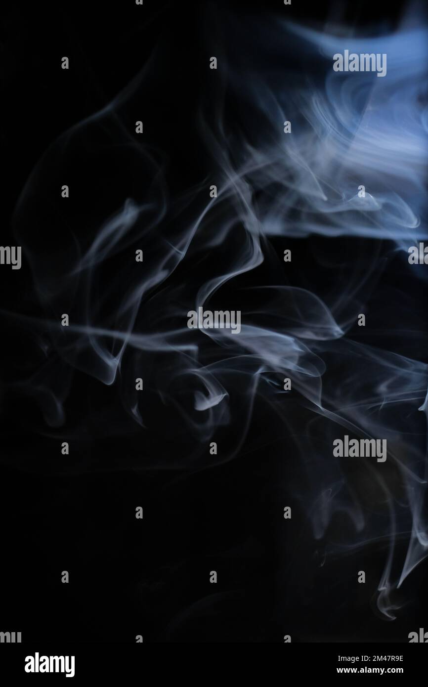 Graceful swirls of white smoke isolated from black background. Close-up of vapor. Soft focus and texture from vintage lens. Abstract graphic resource. Stock Photo