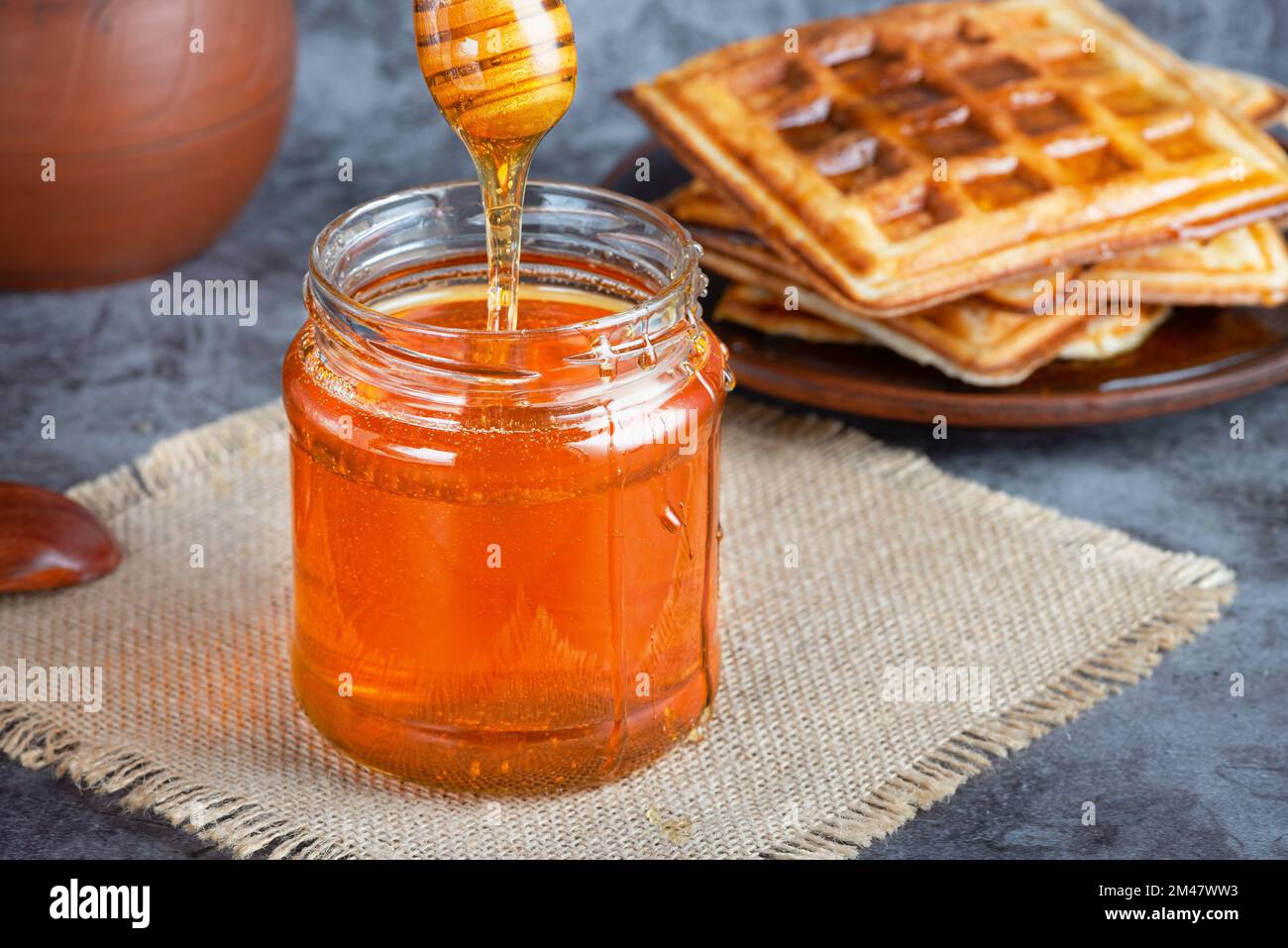 Honey in jar with honey dipper and belgian waffles Stock Photo Alamy